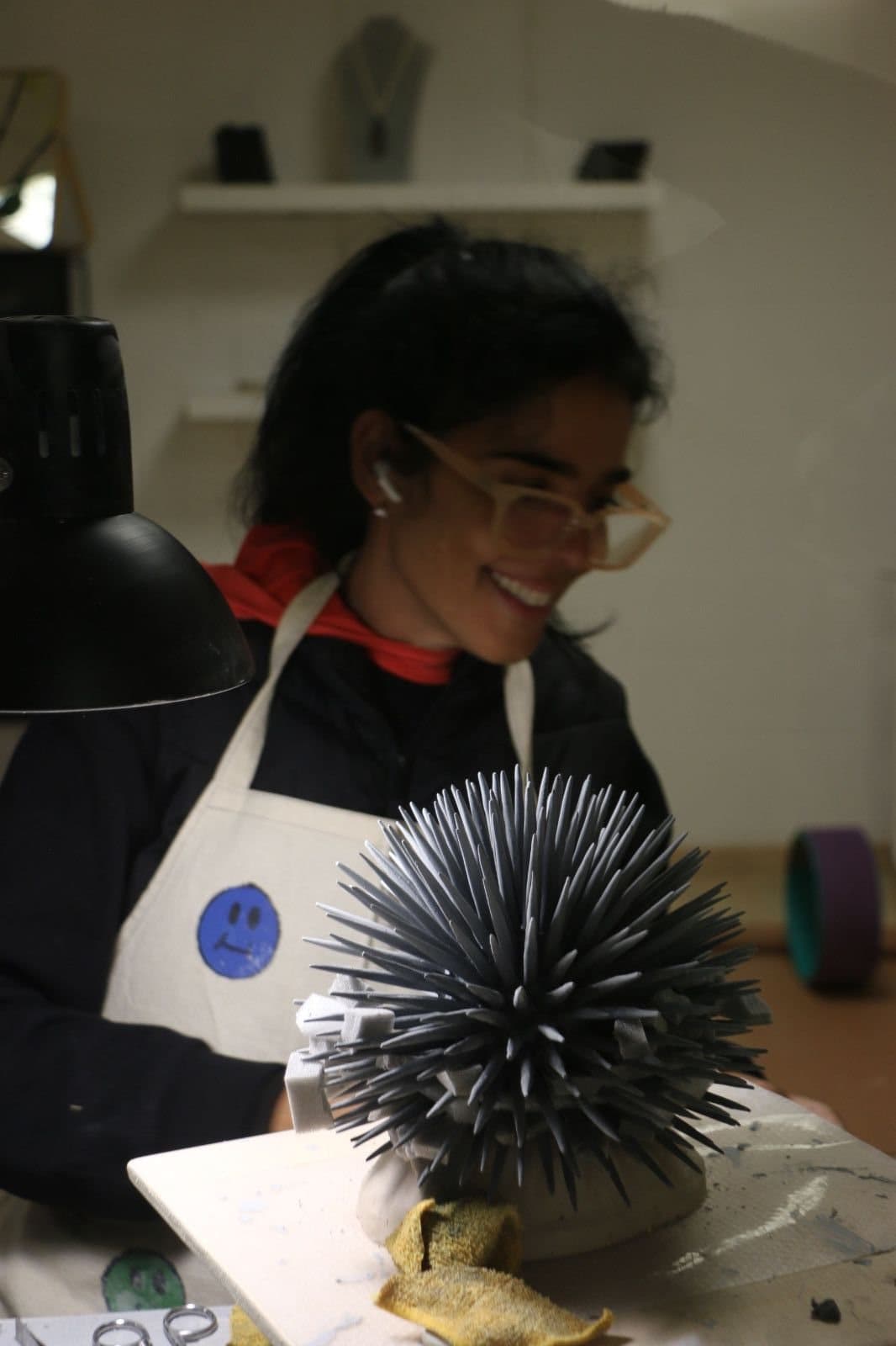 Renata at her workbench, holding a porcelain sea urchin